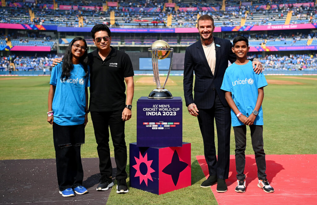 Sachin Tendulkar and David Beckham with two children in Unicef blue tshirts on the football pitch in Mumbai.