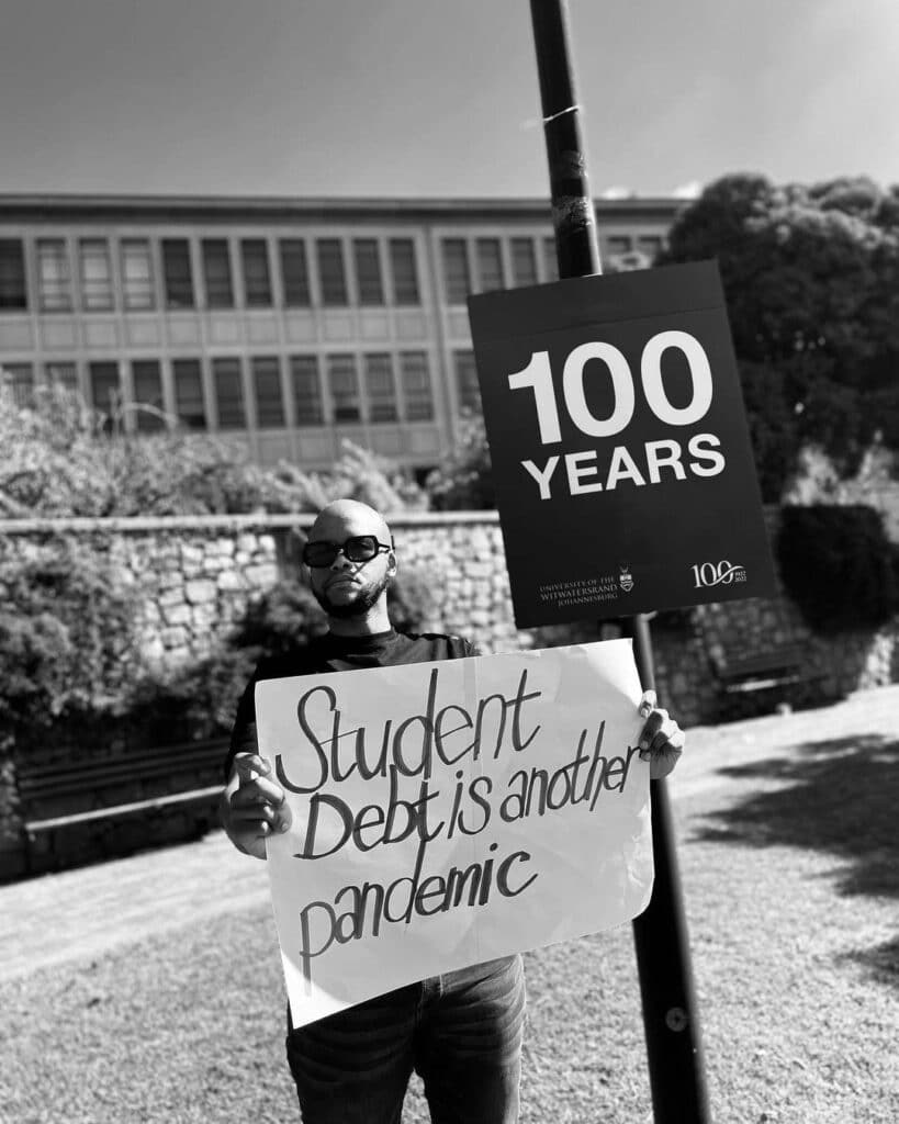 Student with protest banner outside university saying "Student debt is another pandemic"