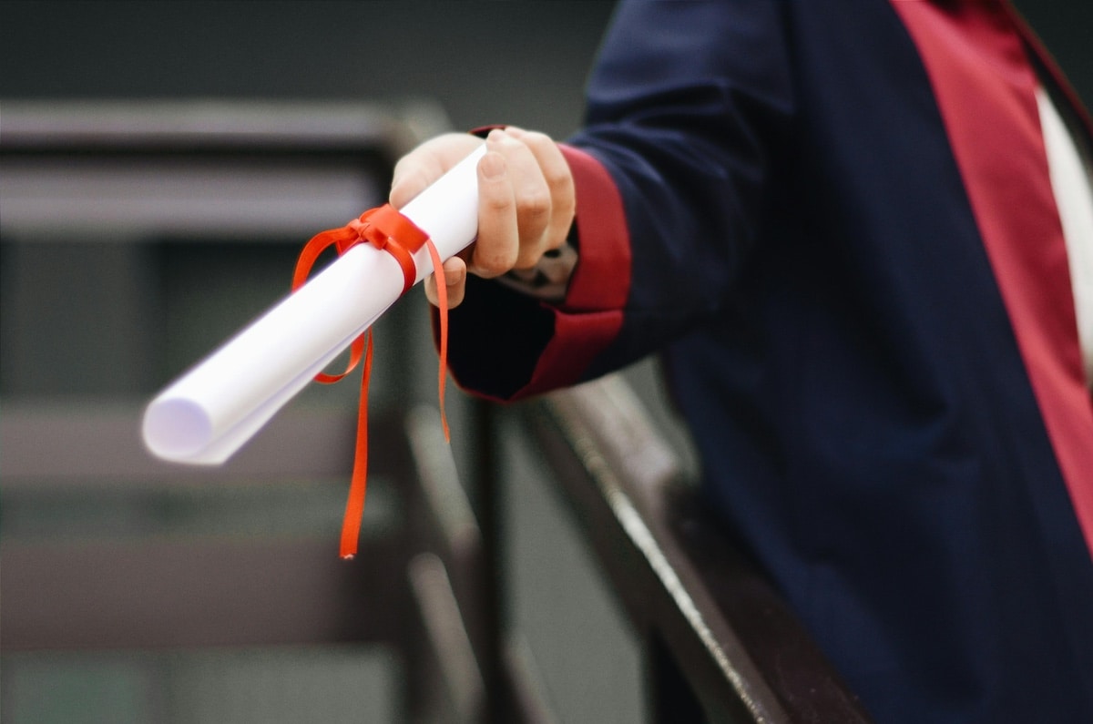 Graduate wearing a formal gown, holding a scroll.