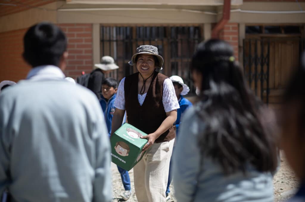 Tatiana holding a discussion box outside with school children near Uru Uru, Bolivia.