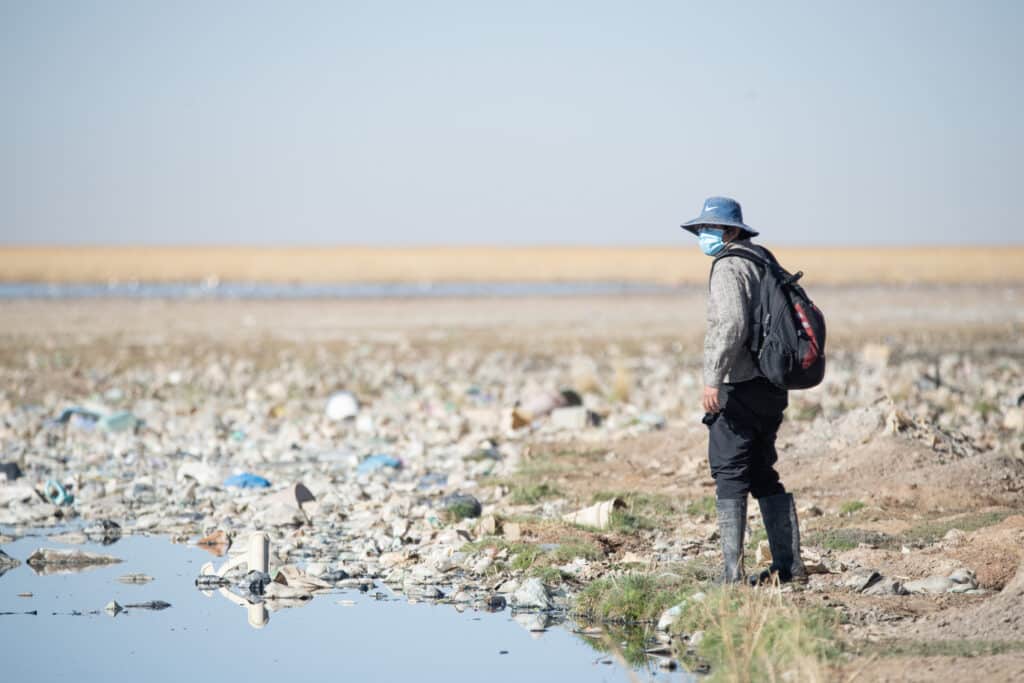 A person stands next to the polluted Uru Uru lake in Bolivia.