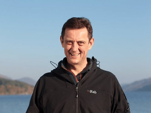 Alan Clayton in a black coat standing with Loch Ness in the background.
